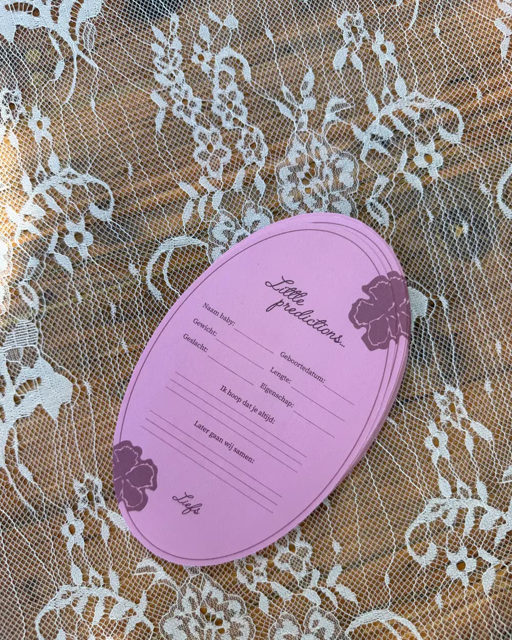 Roze babyshower-voorspellingskaart op kanten tafellinnen