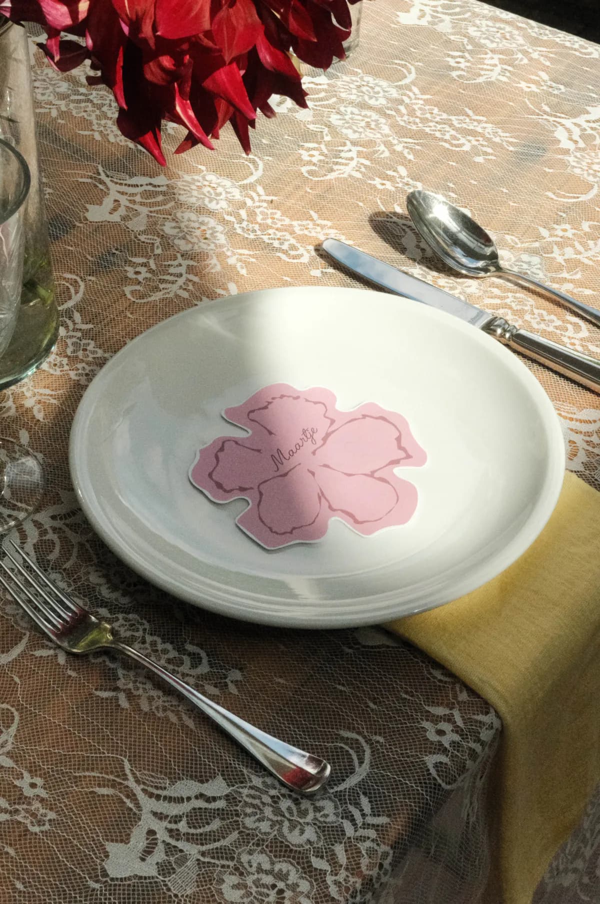 Vintage servies met een roze bloemkaartje op kanten tafellinnen