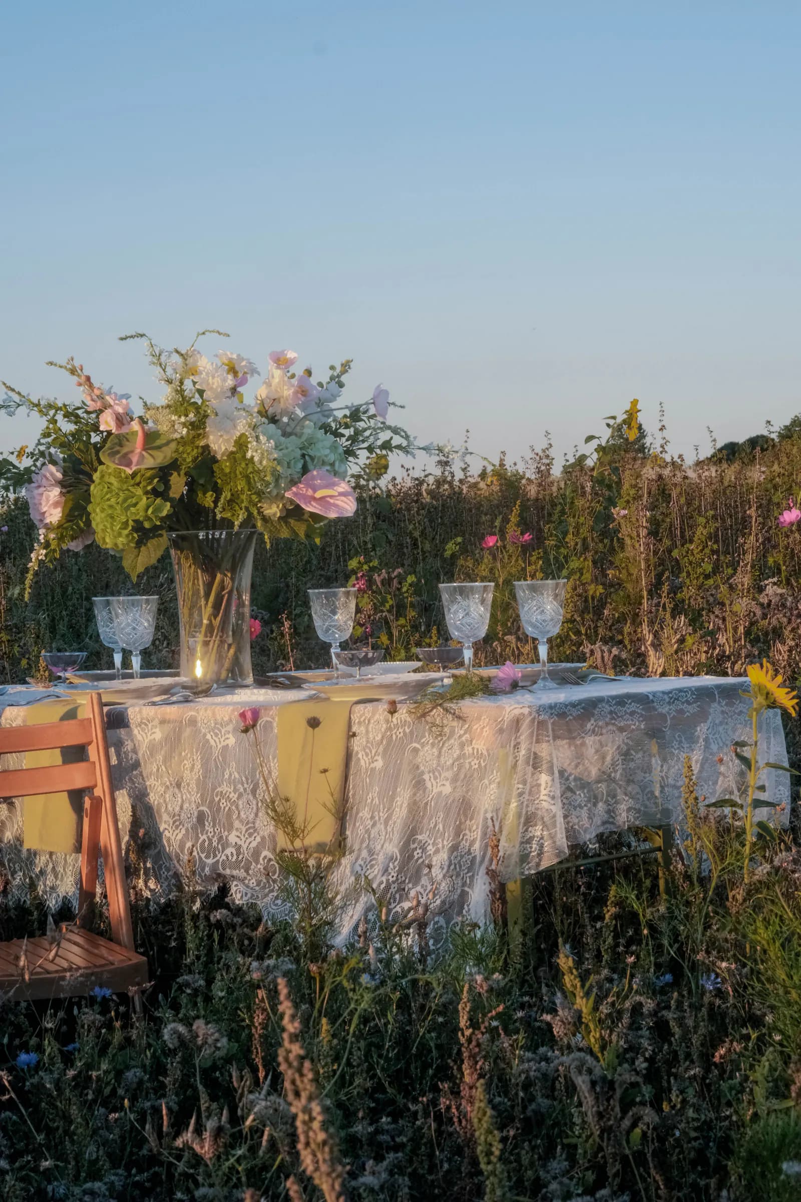 Lange feestelijk gedekte tafel tussen kleurrijke bloemen