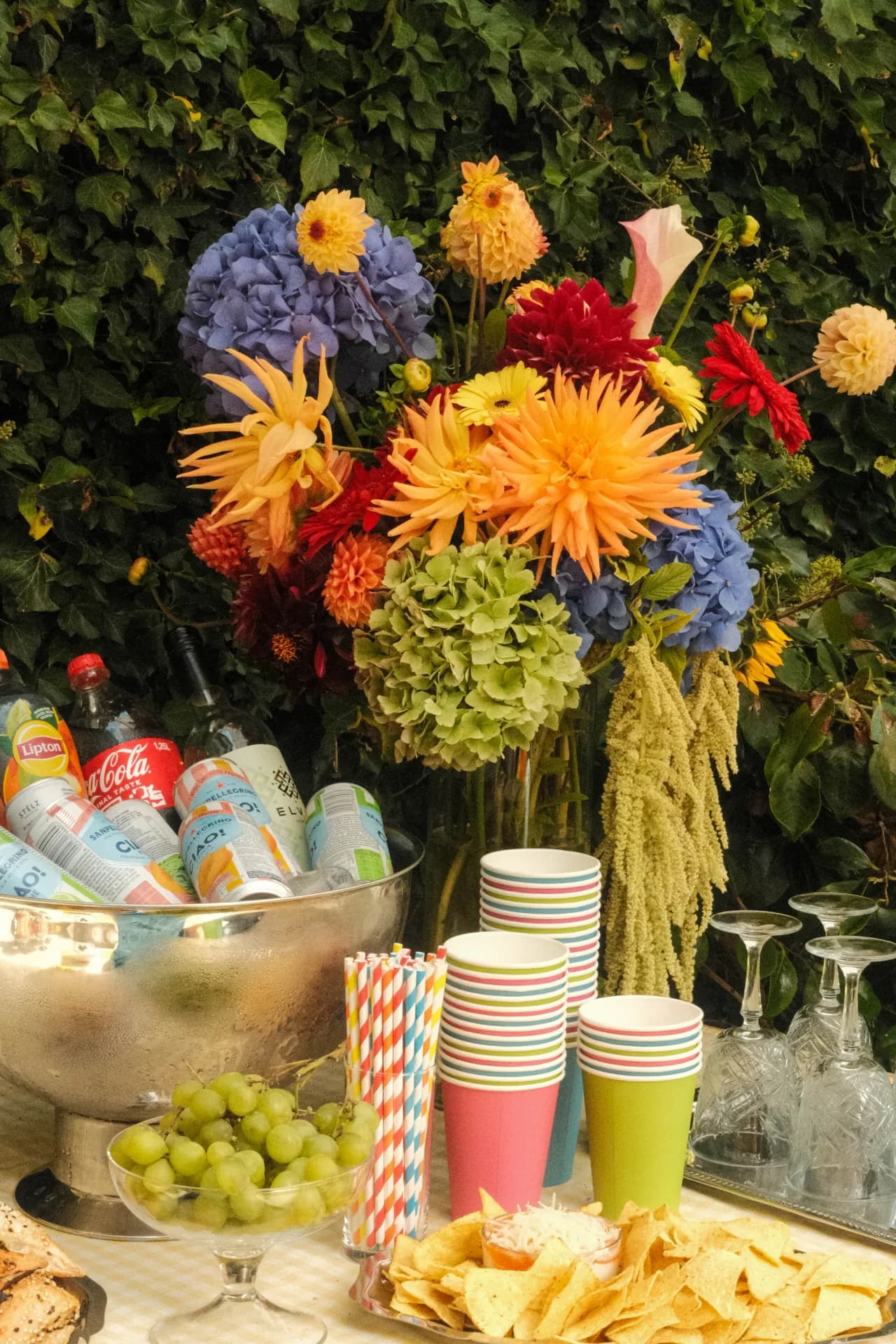 Kleurrijk bloemstuk boven een feestelijk buffet met drankjes en servies