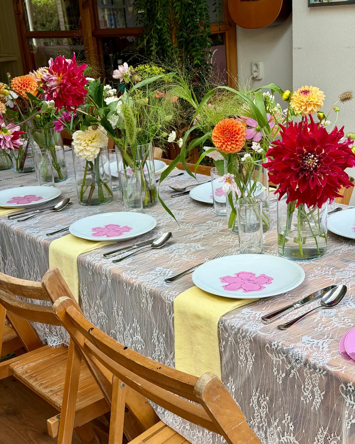 Gedekte tafel met kleurrijke dahlia's, kanten tafellinnen en vintage servies